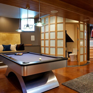 This is an example of a modern look-out basement in Chicago with brown walls, concrete flooring and orange floors.