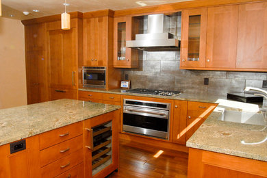 Mid-sized minimalist l-shaped medium tone wood floor open concept kitchen photo in Denver with an undermount sink, beaded inset cabinets, medium tone wood cabinets, granite countertops, gray backsplash, stone tile backsplash, stainless steel appliances and an island