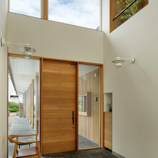 他の地域の片開きドアコンテンポラリースタイルのおしゃれな玄関ホール (白い壁、木目調のドア、黒い床) の写真