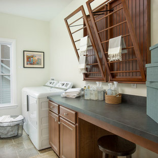 Inspiration for a medium sized classic single-wall separated utility room in Columbus with recessed-panel cabinets, medium wood cabinets, laminate countertops, white walls, travertine flooring, a side by side washer and dryer and green worktops.