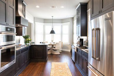 Example of a mid-sized trendy u-shaped dark wood floor and brown floor eat-in kitchen design in Austin with an undermount sink, recessed-panel cabinets, stainless steel appliances, a peninsula, dark wood cabinets, black backsplash and black countertops