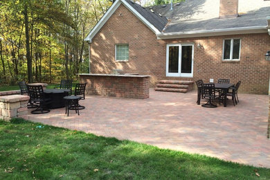 Example of a large mountain style backyard concrete paver patio kitchen design in Columbus