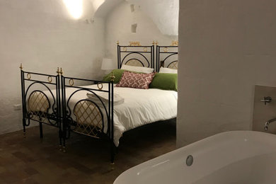 Foto di un'ampia camera matrimoniale mediterranea con pareti bianche, camino classico, cornice del camino in intonaco, soffitto a volta e pareti in mattoni