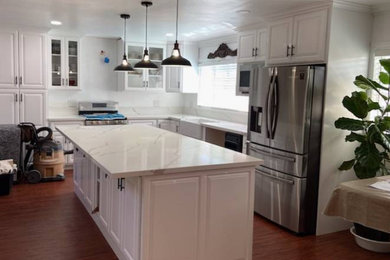 Inspiration for a transitional l-shaped eat-in kitchen remodel in Los Angeles with white cabinets, quartz countertops, an island and white countertops