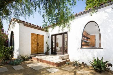 Small tuscan concrete floor and gray floor entryway photo in Los Angeles with a medium wood front door and white walls