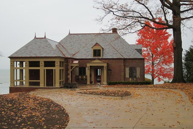 Mid-sized elegant brown two-story brick house exterior photo in Cleveland with a hip roof and a tile roof