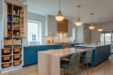 Example of a large transitional galley light wood floor and brown floor eat-in kitchen design in Columbus with a farmhouse sink, flat-panel cabinets, blue cabinets, quartz countertops, white backsplash, ceramic backsplash, paneled appliances, two islands and white countertops
