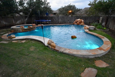 Hot tub - large transitional backyard stone and custom-shaped hot tub idea in Austin