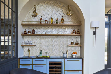 Example of a small transitional single-wall wet bar design in Chicago with an undermount sink, flat-panel cabinets, blue cabinets, soapstone countertops, beige backsplash, stone tile backsplash and black countertops