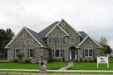 Example of a large classic gray two-story stone exterior home design in Other with a clipped gable roof