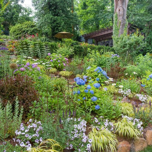Immagine di un ampio giardino chic esposto a mezz'ombra in estate con un muro di contenimento, un pendio, una collina o una riva e pavimentazioni in pietra naturale