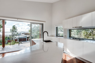 Photo of a mid-sized contemporary galley eat-in kitchen in Central Coast with a drop-in sink, flat-panel cabinets, white cabinets, quartz benchtops, dark hardwood floors, with island and white benchtop.