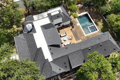 Example of a large minimalist two-story house exterior design in Austin with a hip roof, a shingle roof and a black roof
