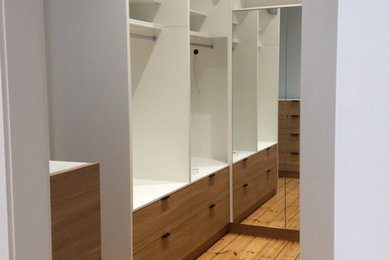 Inredning av ett modernt mellanstort walk-in-closet för könsneutrala, med ljust trägolv