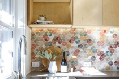 Foto di una piccola cucina minimal con lavello da incasso, ante lisce, ante bianche, top in quarzo composito, paraspruzzi multicolore, paraspruzzi con piastrelle in ceramica, elettrodomestici in acciaio inossidabile, pavimento in laminato, nessuna isola, pavimento marrone e top grigio