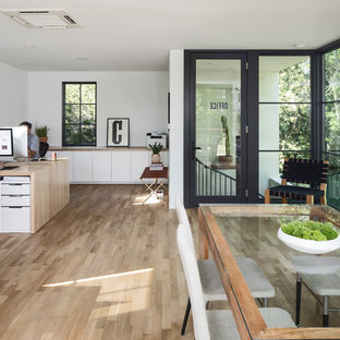 This is an example of a small modern home studio in Austin with white walls, light hardwood flooring, no fireplace, a brick fireplace surround, a built-in desk and white floors.