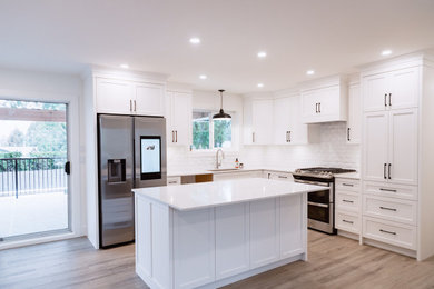 Example of a mid-sized classic l-shaped vinyl floor and gray floor eat-in kitchen design in Vancouver with an undermount sink, shaker cabinets, white cabinets, quartz countertops, white backsplash, ceramic backsplash, stainless steel appliances, an island and white countertops