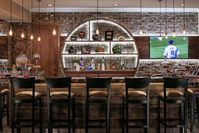 Photo of a large industrial single-wall seated home bar in Omaha with open cabinets, brick splashback, concrete floors, grey floor, medium wood cabinets and granite benchtops.