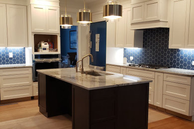 Klassisk inredning av ett mellanstort vit vitt kök, med en undermonterad diskho, skåp i shakerstil, vita skåp, bänkskiva i kvarts, blått stänkskydd, stänkskydd i porslinskakel, rostfria vitvaror, ljust trägolv och en köksö