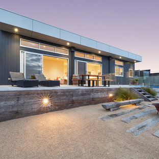 This is an example of a beach style one-storey black house exterior in Melbourne with a flat roof.