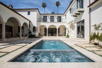Inspiration for a mid-sized mediterranean courtyard rectangular pool in San Diego with a water feature and concrete slab.