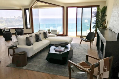 Large trendy formal and open concept medium tone wood floor and brown floor living room photo in Orange County with beige walls, a standard fireplace, a metal fireplace and no tv