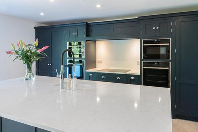 Design ideas for a large contemporary l-shaped open plan kitchen in Kent with recessed-panel cabinets, blue cabinets, quartzite benchtops, white splashback, stainless steel appliances, with island and white benchtop.