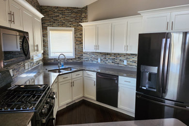 Example of a mid-sized transitional u-shaped dark wood floor and brown floor open concept kitchen design in Other with an undermount sink, shaker cabinets, yellow cabinets, quartzite countertops, brown backsplash, glass tile backsplash, stainless steel appliances, a peninsula and gray countertops