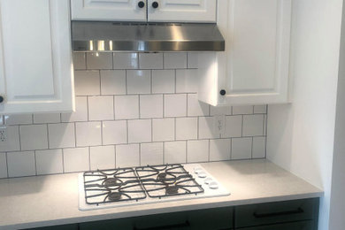 Example of a kitchen design in Salt Lake City with shaker cabinets, green cabinets, quartz countertops, white backsplash, subway tile backsplash, white appliances, an island and white countertops