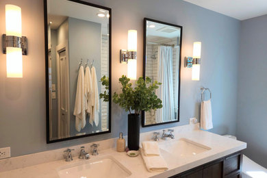 Idéer för att renovera ett mellanstort amerikanskt flerfärgad flerfärgat en-suite badrum, med släta luckor, skåp i mörkt trä, ett badkar i en alkov, en dusch i en alkov, en toalettstol med hel cisternkåpa, vit kakel, keramikplattor, blå väggar, klinkergolv i porslin, ett undermonterad handfat, bänkskiva i kvarts, flerfärgat golv och dusch med duschdraperi