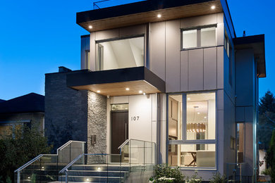 Photo of a mid-sized modern two-storey grey house exterior in Vancouver with concrete fiberboard siding, a flat roof and a tile roof.