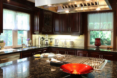 Inspiration for a mid-sized transitional l-shaped enclosed kitchen remodel in Austin with a double-bowl sink, raised-panel cabinets, dark wood cabinets, granite countertops, beige backsplash, travertine backsplash, stainless steel appliances and an island