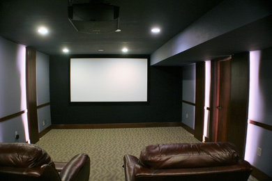 This is an example of a mid-sized contemporary enclosed home theatre in Boston with grey walls, carpet and a projector screen.