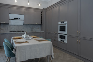 Inspiration for a mid-sized transitional l-shaped eat-in kitchen in Moscow with an undermount sink, beaded inset cabinets, grey cabinets, quartz benchtops, grey splashback, white appliances, laminate floors, no island, grey floor and grey benchtop.