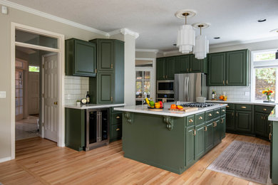 Example of a mid-sized transitional light wood floor and multicolored floor open concept kitchen design in Portland with an undermount sink, raised-panel cabinets, green cabinets, quartz countertops, yellow backsplash, ceramic backsplash, stainless steel appliances, an island and white countertops