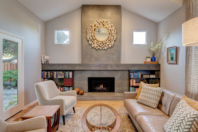 Design ideas for a mid-sized contemporary formal open concept living room in San Francisco with a standard fireplace, a concrete fireplace surround, grey walls, light hardwood floors and no tv.
