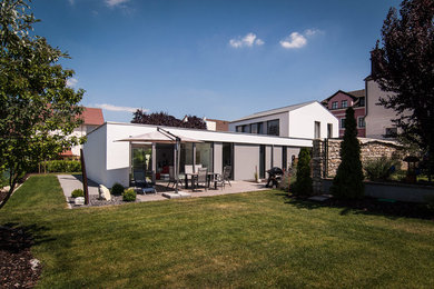 Mittelgroßes, Zweistöckiges Modernes Haus mit Putzfassade, weißer Fassadenfarbe und Satteldach in Sonstige