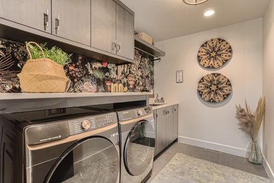 Small minimalist single-wall porcelain tile, black floor and wallpaper laundry room photo in Denver with an undermount sink, flat-panel cabinets, black cabinets, quartz countertops, white walls, a side-by-side washer/dryer and white countertops