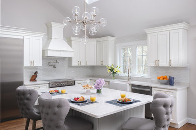 Large transitional l-shaped medium tone wood floor and brown floor kitchen photo in Boston with white cabinets, white backsplash, an island and white countertops