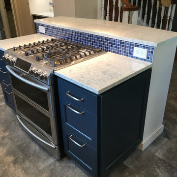 White cabinets with dark blue island cabinets. double-oven range