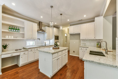 Inspiration for a mid-sized transitional u-shaped medium tone wood floor and orange floor eat-in kitchen remodel in Houston with an undermount sink, white cabinets, granite countertops, white backsplash, subway tile backsplash, stainless steel appliances, an island, white countertops and raised-panel cabinets