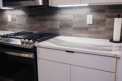 Example of a small trendy single-wall dark wood floor and black floor eat-in kitchen design in Charlotte with flat-panel cabinets, white cabinets, quartz countertops, gray backsplash, porcelain backsplash, stainless steel appliances, an island, multicolored countertops and an undermount sink