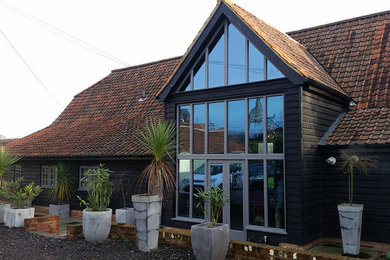 Design ideas for a large and black rustic two floor house exterior with wood cladding and a pitched roof.