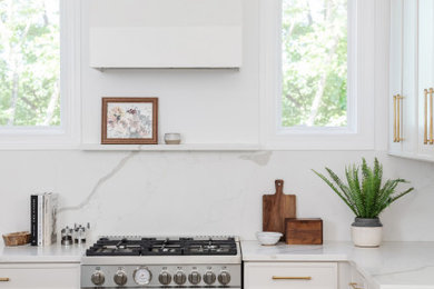 Inspiration for a mid-sized transitional l-shaped medium tone wood floor eat-in kitchen remodel in Charlotte with shaker cabinets, white cabinets, white backsplash, stainless steel appliances, an island and white countertops