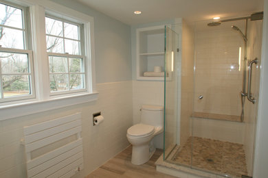 Bathroom - mid-sized transitional master white tile and ceramic tile porcelain tile, brown floor, double-sink and vaulted ceiling bathroom idea in New York with shaker cabinets, white cabinets, a one-piece toilet, white walls, an undermount sink, quartz countertops, white countertops and a built-in vanity