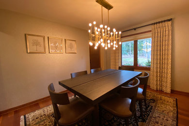 Example of a mid-sized minimalist medium tone wood floor, brown floor and wallpaper enclosed dining room design in Milwaukee with beige walls