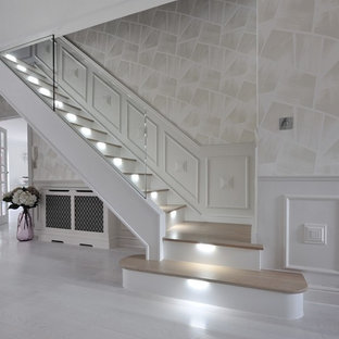Inspiration for a large contemporary wood curved glass railing staircase in London with glass risers.