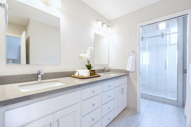 Inspiration for a large contemporary ensuite bathroom with shaker cabinets, white cabinets, all types of shower, grey tiles, all types of wall tile, white walls, ceramic flooring, a submerged sink, quartz worktops, grey floors, a sliding door, grey worktops, an enclosed toilet, double sinks and a built in vanity unit.