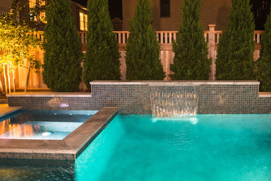 Esempio di una grande piscina contemporanea rettangolare dietro casa con fontane e piastrelle