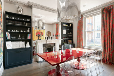This is an example of a medium sized bohemian enclosed dining room in London with white walls, medium hardwood flooring, a standard fireplace and a stone fireplace surround.